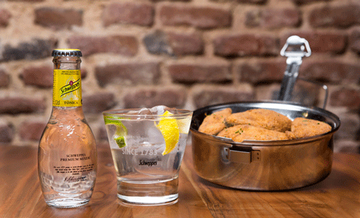 Medio gin-tonic de Schweppes con las alitas de pollo de Lovnis