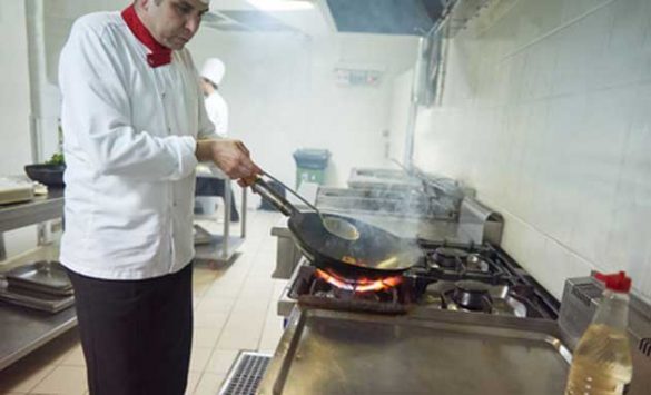 Cocinero con una sartén al fuego