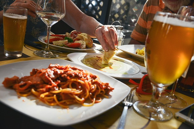 Profesionalhoreca, comiendo en mesa de restaurante con platos y cerveza