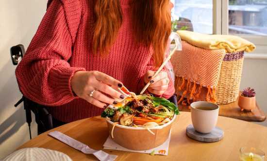 profesionalhoreca, chica comiendo un bol de plato vegetal de Just Eat a domicilio. Platos vegetales