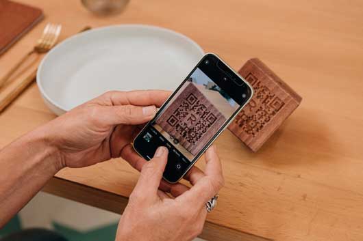 Profesional Horeca, leyendo un QR dinámico en un cubo de madera de Sibaritat