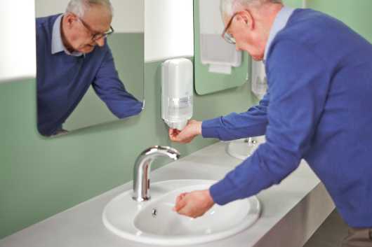 Profesional Hoerca, usando un dispensador de jabón Tork en un aseo público